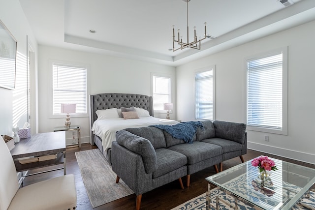bedroom featuring a raised ceiling, a notable chandelier, dark wood-style floors, and baseboards