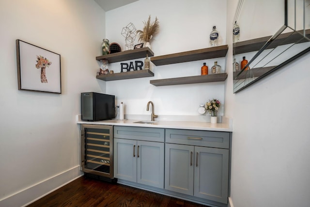 bar with wine cooler, a sink, dark wood-style floors, indoor wet bar, and baseboards