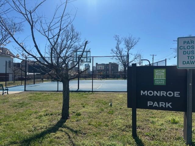 view of tennis court featuring community basketball court, fence, and a yard
