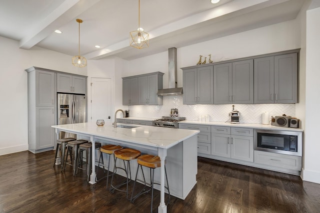kitchen with a sink, wall chimney exhaust hood, stainless steel fridge, gray cabinetry, and built in microwave