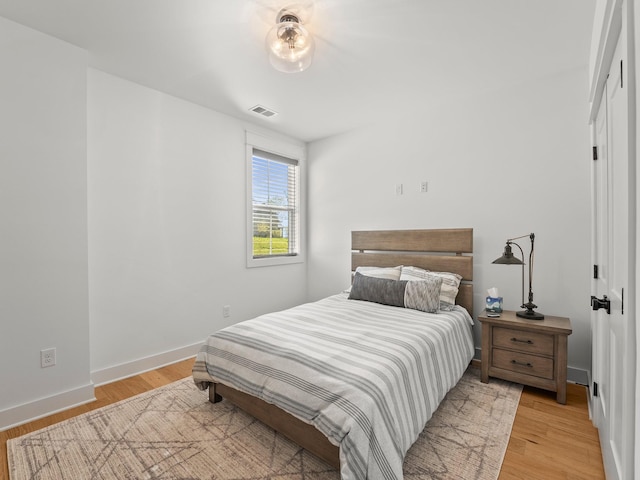 bedroom featuring visible vents, light wood finished floors, and baseboards