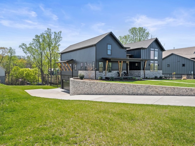 back of property featuring an attached garage, a lawn, driveway, and board and batten siding