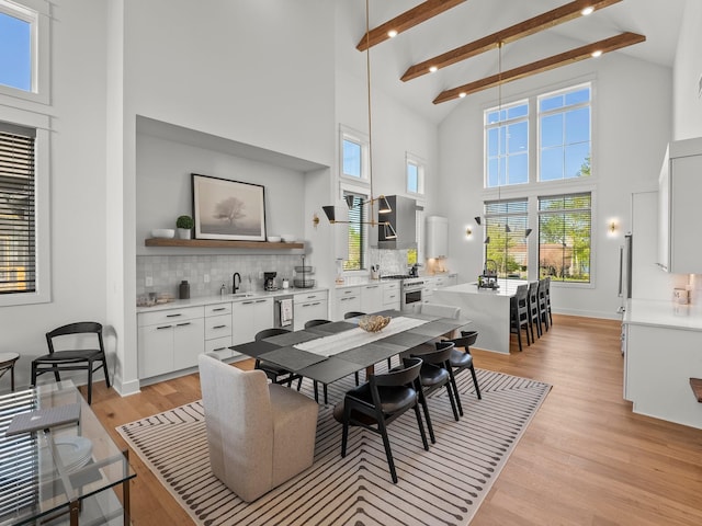 dining space with high vaulted ceiling, a healthy amount of sunlight, beamed ceiling, and light wood-style flooring