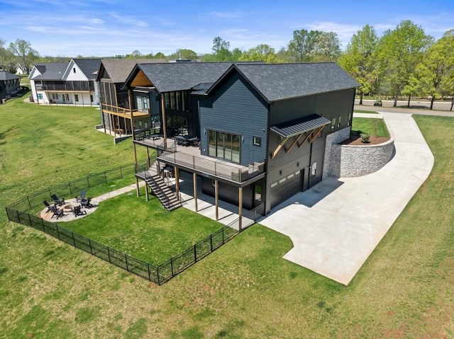 back of property featuring concrete driveway, a deck, an outdoor fire pit, a garage, and stairs