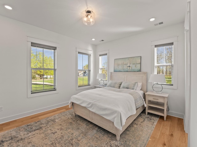 bedroom featuring visible vents, light wood finished floors, and multiple windows