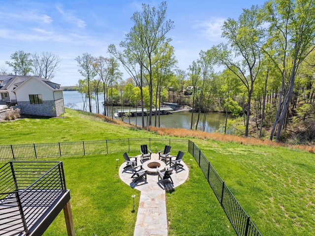 view of yard featuring a fire pit, fence, a water view, and a patio area