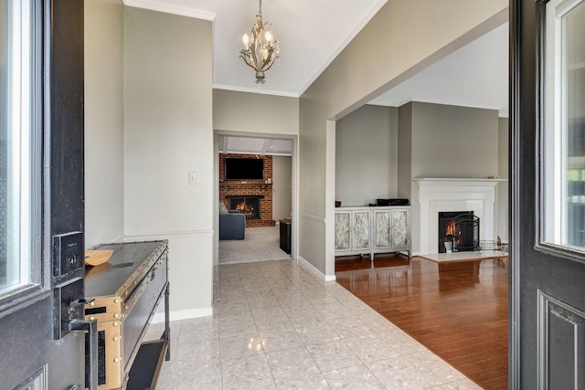 interior space with a notable chandelier, a brick fireplace, baseboards, and crown molding
