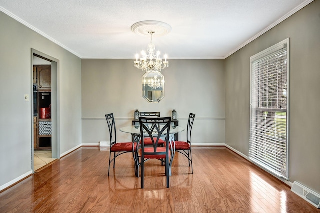 dining space featuring ornamental molding, visible vents, a chandelier, and wood finished floors