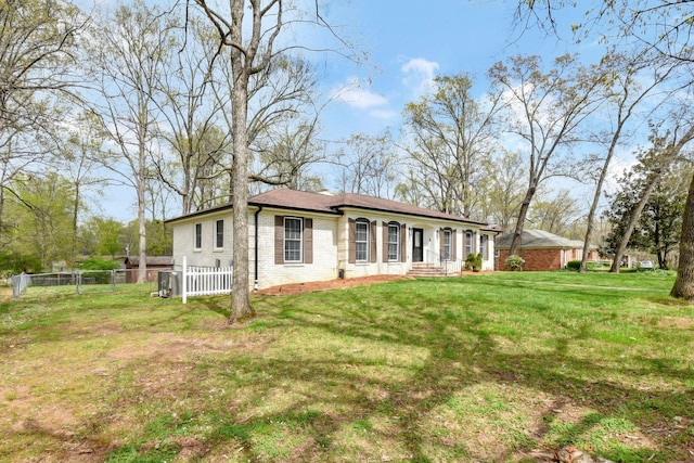 view of front facade with brick siding, fence, and a front lawn