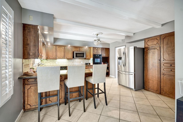 kitchen featuring a peninsula, appliances with stainless steel finishes, baseboards, backsplash, and beam ceiling