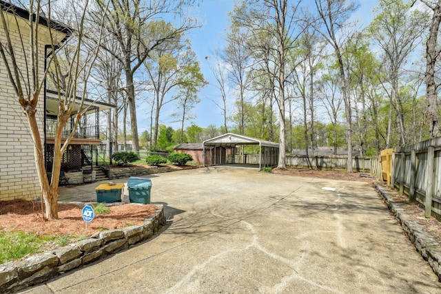 view of yard featuring a detached carport, fence, and concrete driveway