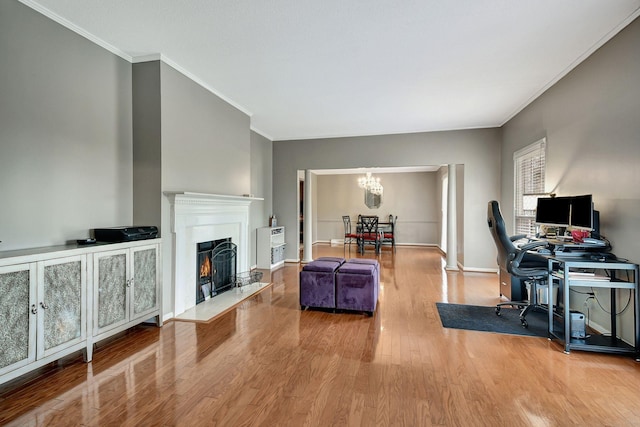 home office with ornamental molding, a warm lit fireplace, wood finished floors, a notable chandelier, and baseboards