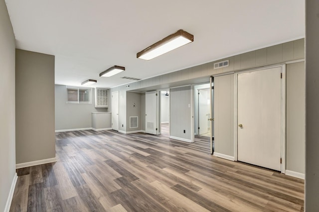 below grade area with wood finished floors, baseboards, and visible vents