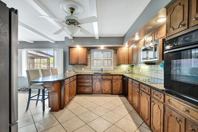 kitchen featuring ceiling fan, a kitchen breakfast bar, a peninsula, black appliances, and a sink