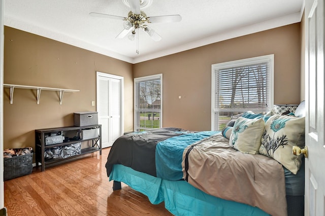 bedroom with a closet, ceiling fan, multiple windows, and wood finished floors