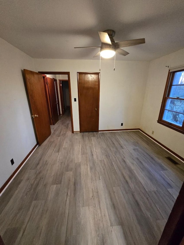 unfurnished bedroom with baseboards, visible vents, and wood finished floors