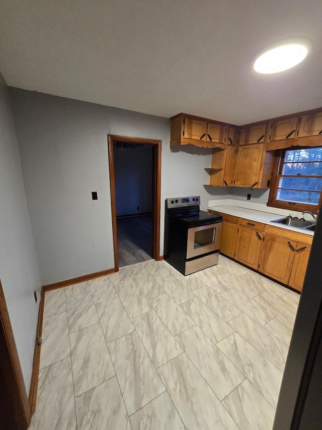 kitchen featuring light countertops, stainless steel range with electric stovetop, a sink, and marble finish floor