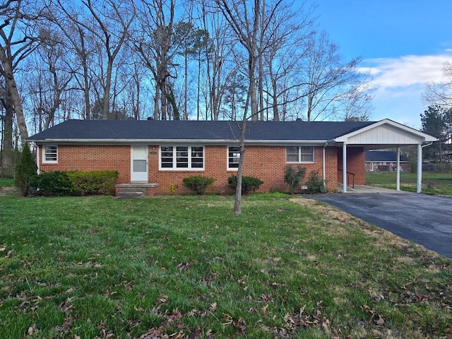 ranch-style home with an attached carport, a front yard, brick siding, and driveway