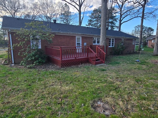 rear view of property with a deck, brick siding, and a yard