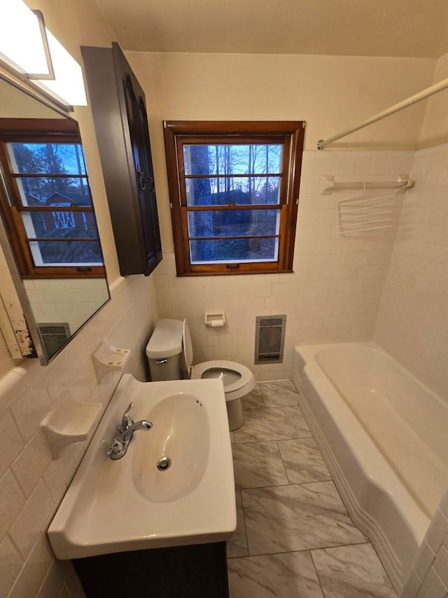full bath with vanity, tile walls, toilet, bathing tub / shower combination, and marble finish floor