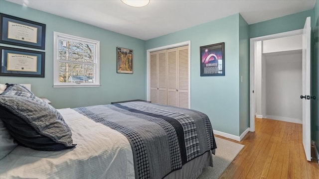 bedroom with a closet, light wood-style flooring, and baseboards