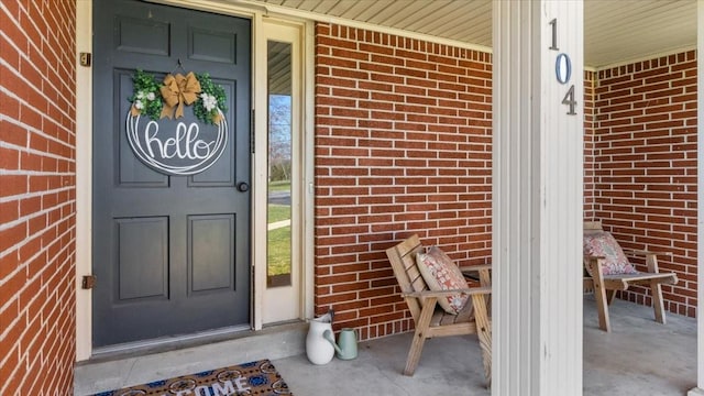 entrance to property with a porch and brick siding