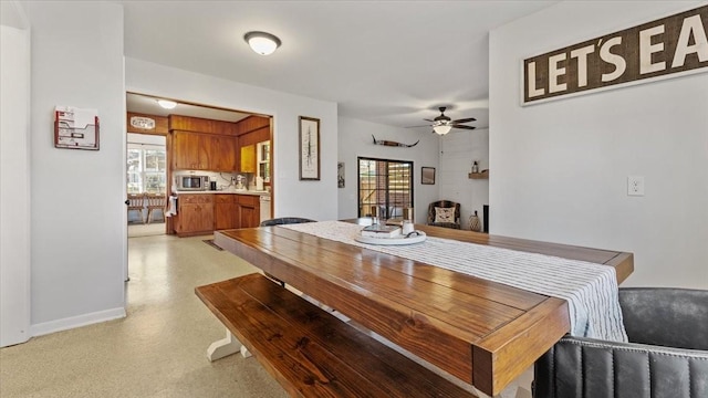 dining area with baseboards, ceiling fan, and light floors