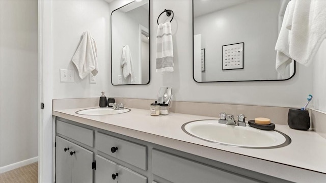 full bath featuring double vanity, baseboards, and a sink