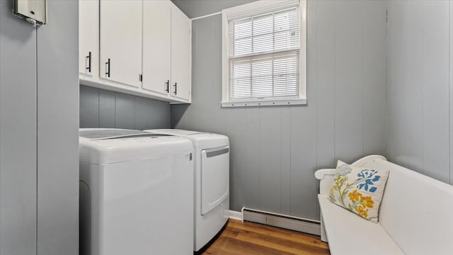 laundry room with a baseboard radiator, washing machine and dryer, wood finished floors, and cabinet space