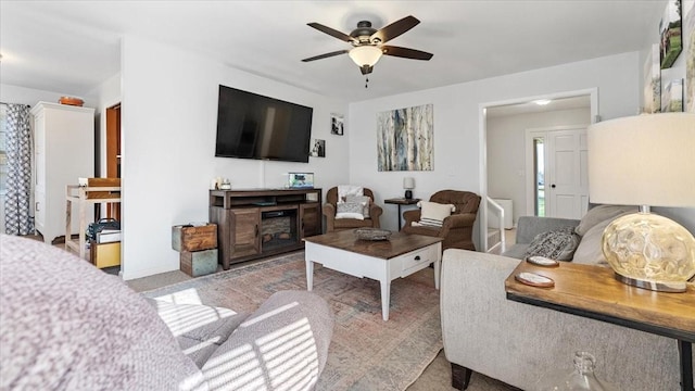 living room with a fireplace, ceiling fan, and baseboards