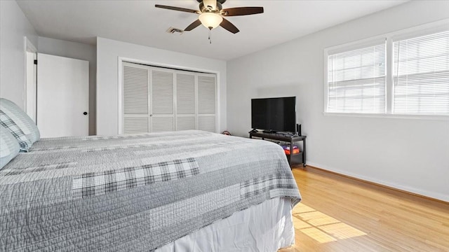 bedroom featuring a closet, visible vents, light wood-style flooring, baseboards, and ceiling fan