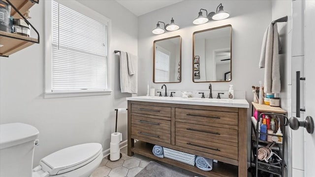 bathroom with a sink, double vanity, toilet, and tile patterned flooring