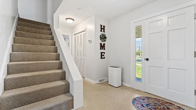 foyer featuring light colored carpet, baseboards, stairs, and visible vents