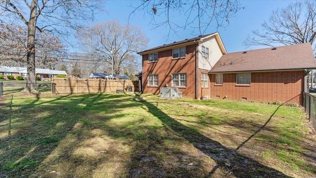 rear view of property with a lawn, fence, brick siding, and crawl space