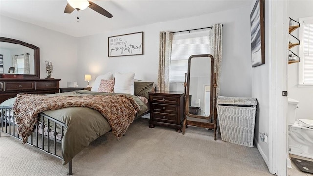 bedroom with a ceiling fan, light carpet, and ensuite bath