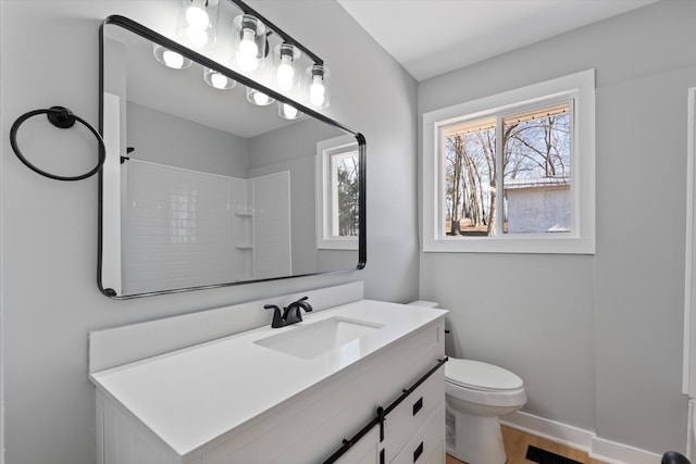 bathroom with a shower, vanity, toilet, baseboards, and visible vents