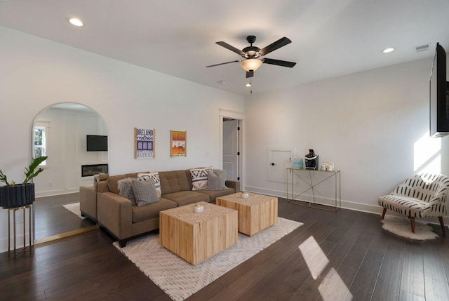 living area featuring ceiling fan, dark wood-style flooring, arched walkways, baseboards, and recessed lighting
