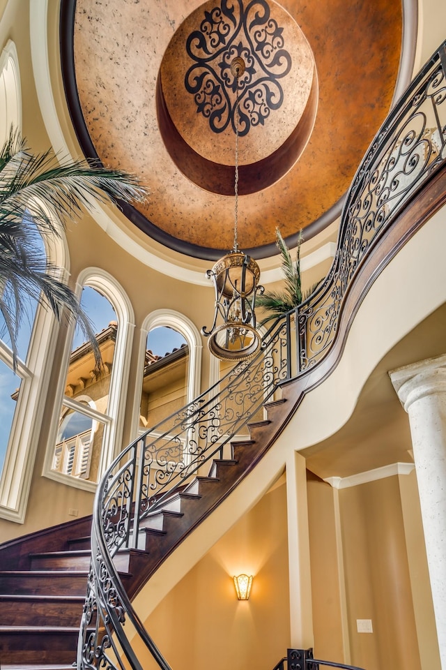 947 Tyne Blvd, Nashville, TN 37220 - staircase with ornamental molding, decorative columns, a tray ceiling, a high ceiling, and an inviting chandelier