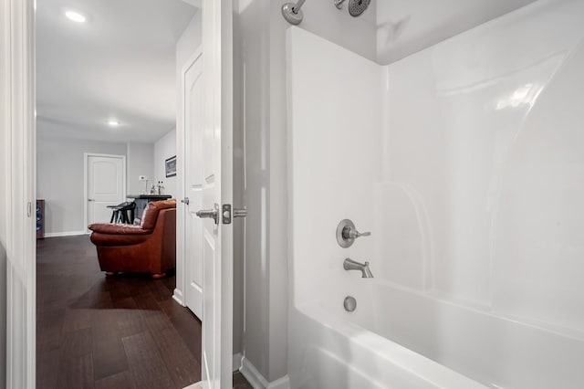 bathroom with baseboards, recessed lighting, wood finished floors, and bathtub / shower combination