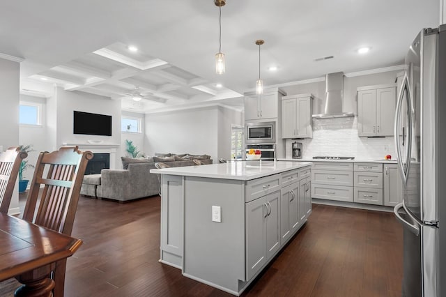 kitchen featuring visible vents, a fireplace, open floor plan, wall chimney range hood, and appliances with stainless steel finishes