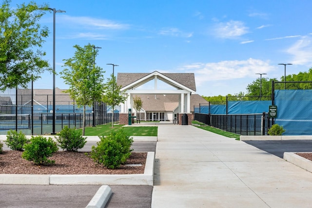 surrounding community with fence, a tennis court, and driveway