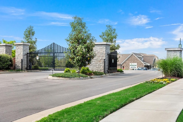 view of street featuring a gate, a gated entry, and curbs