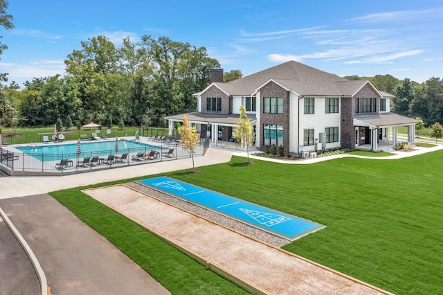 exterior space featuring shuffleboard, a swimming pool, fence, and a lawn