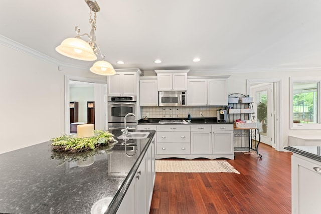kitchen featuring decorative backsplash, crown molding, stainless steel microwave, a sink, and gas stovetop