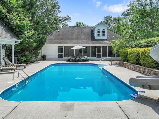 pool featuring a water slide, a sunroom, a patio, and outdoor dining area