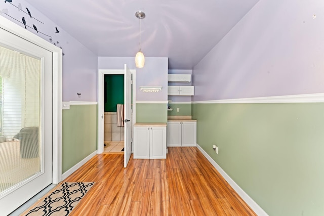 interior space with baseboards, light wood-style flooring, and an AC wall unit