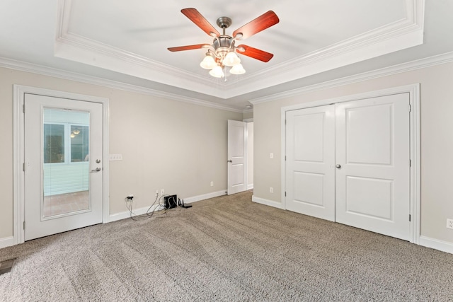 unfurnished bedroom featuring baseboards, ornamental molding, carpet, and a raised ceiling