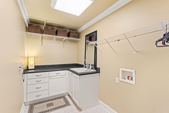 laundry area featuring crown molding, washer hookup, a sink, cabinet space, and light tile patterned floors