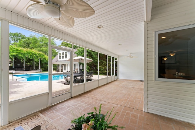 unfurnished sunroom featuring a ceiling fan and plenty of natural light