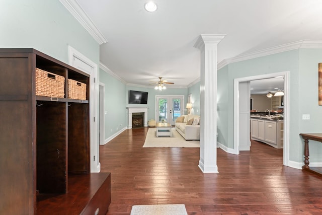 unfurnished living room featuring ornate columns, ornamental molding, dark wood-style floors, and ceiling fan